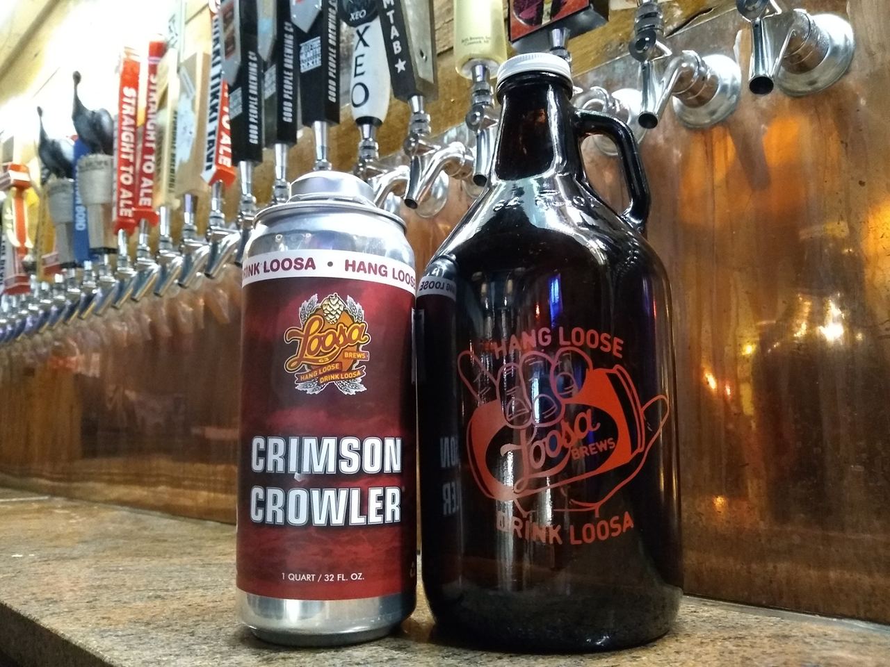 The Crimson Crowler — Loosa Brews 32-oz signature to-go can next to a Loosa Brews growler at the tap wall