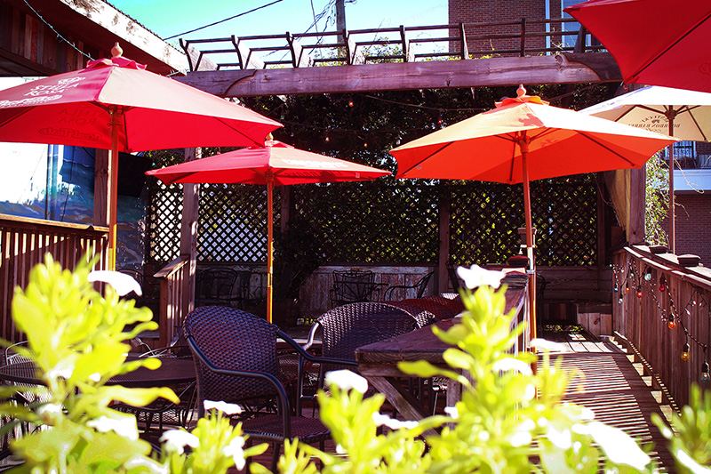 The Hang Loosa patio — bistro tables under red Coca-Cola umbrellas with string lights